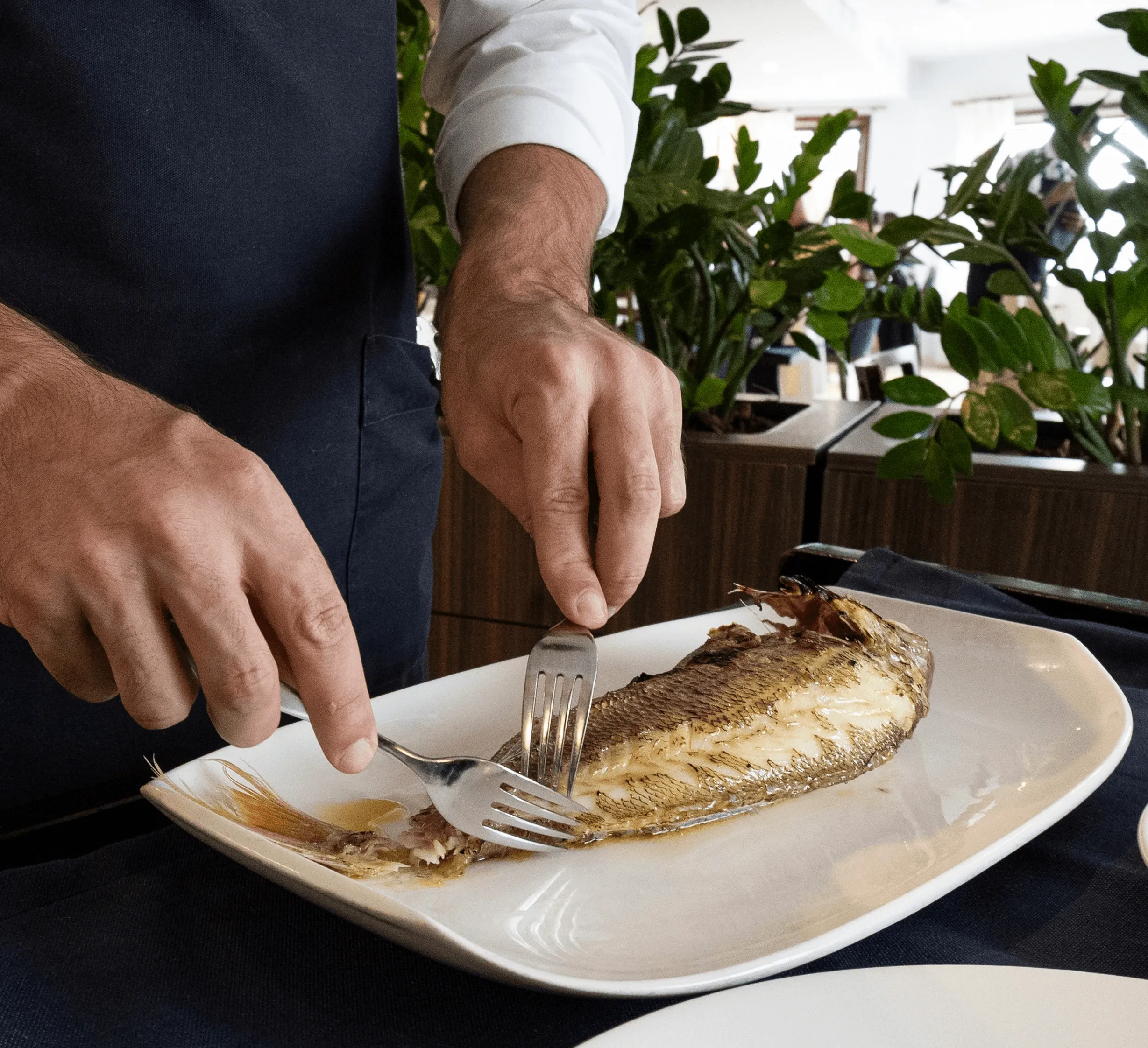 A whole local fish being carefully filleted tableside
